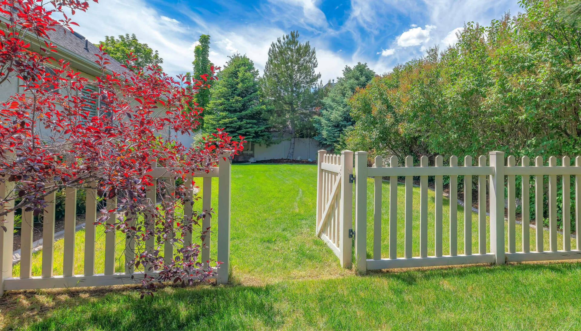 A functional fence gate providing access to a well-maintained backyard, surrounded by a wooden fence in Burlington